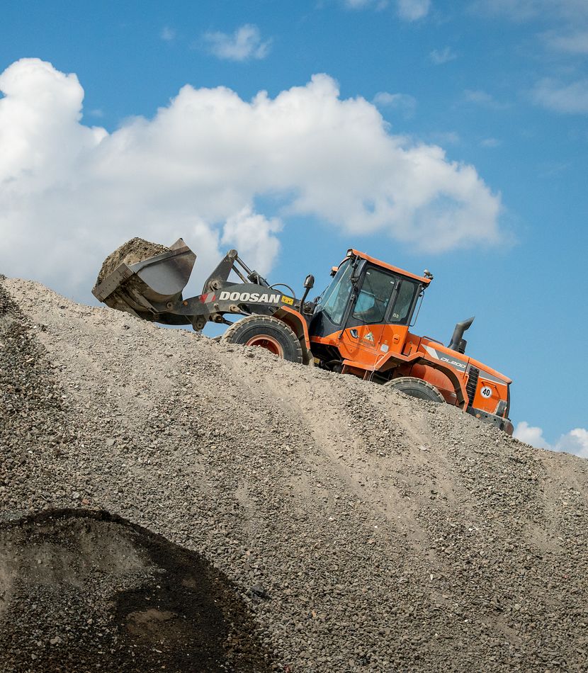 Chargeuse sur pneus Doosan au sommet d'un stock de granulats recyclés